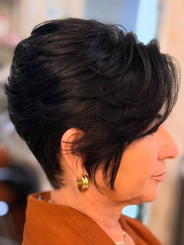 Corte curto estilizado em cabelo escuro, vista de perfil