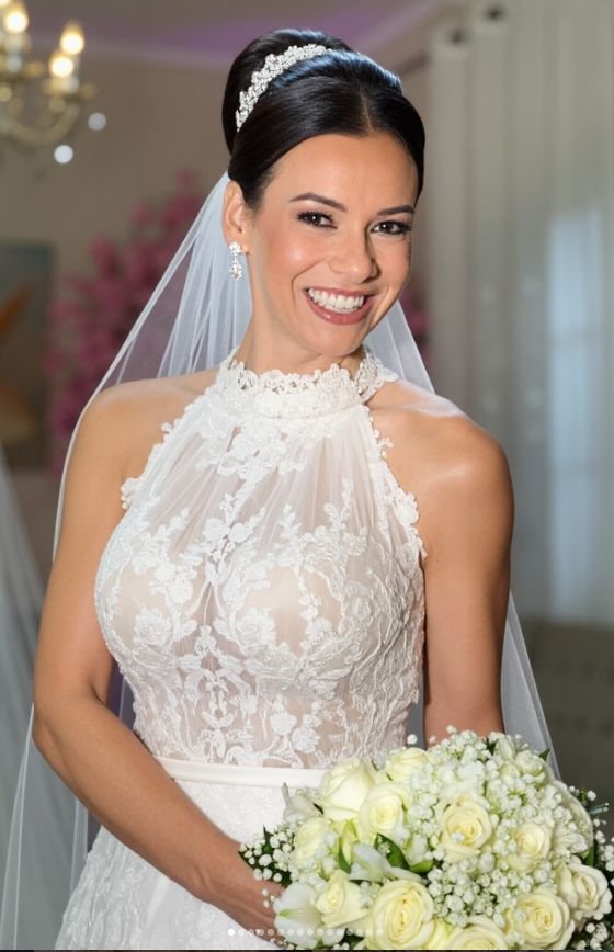 Noiva sorrindo com véu, tiara e buquê de rosas brancas